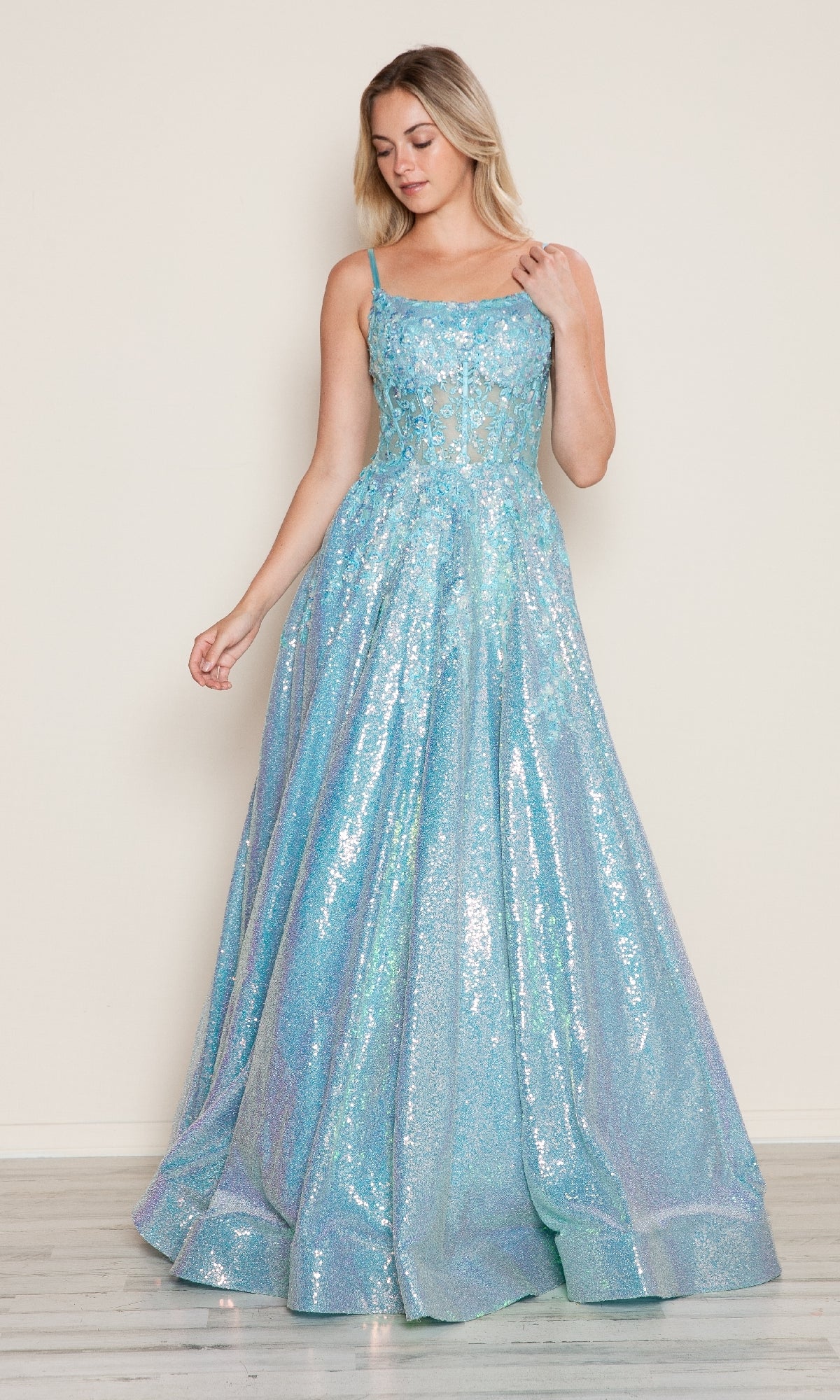 A woman stands against a plain background wearing the Poly USA 9554 Side-Pockets Long Sequin Prom Dress, a light blue, floor-length gown with spaghetti straps.
